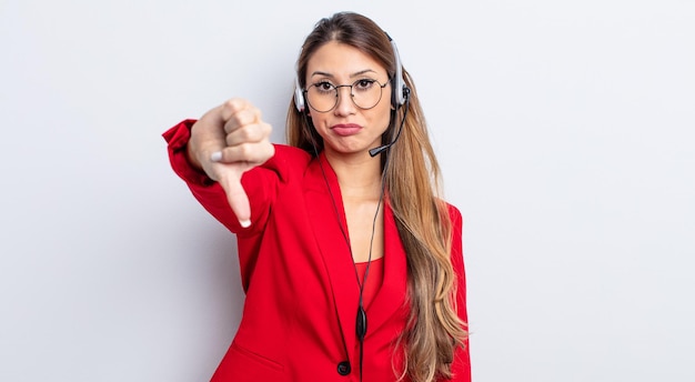 Mujer bonita asiática que se siente cruzada, mostrando los pulgares hacia abajo. concepto de telemarker