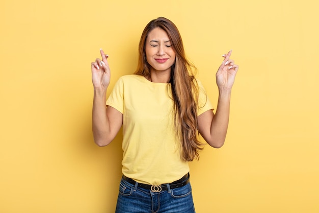 Mujer bonita asiática que se siente nerviosa y esperanzada cruzando los dedos rezando y esperando buena suerte