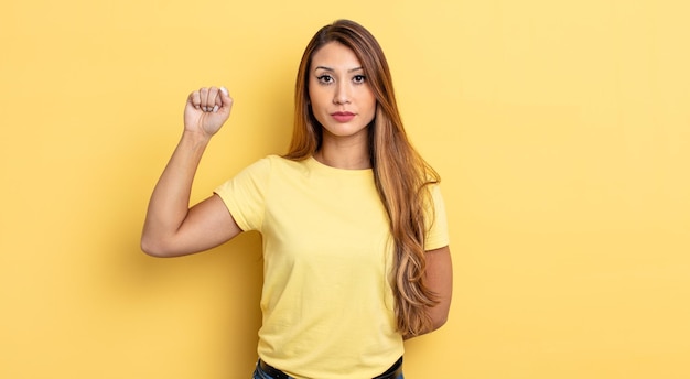 Mujer bonita asiática que se siente seria, fuerte y rebelde, levanta el puño, protesta o lucha por la revolución