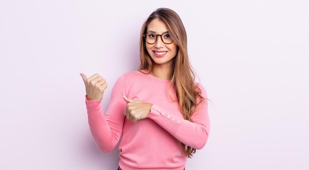 Mujer bonita asiática sonriendo alegre y casualmente señalando el espacio de copia a un lado, sintiéndose feliz y satisfecha