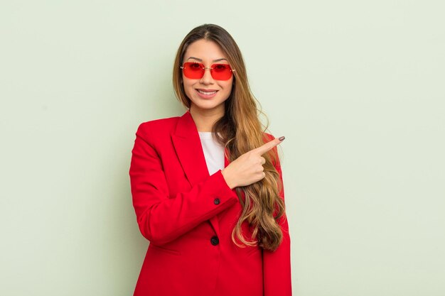 Mujer bonita asiática sonriendo alegremente sintiéndose feliz y señalando el concepto de negocio lateral