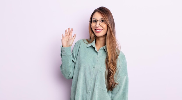 Mujer bonita asiática sonriendo feliz y alegremente, saludando con la mano, dándote la bienvenida y saludándote, o diciéndote adiós