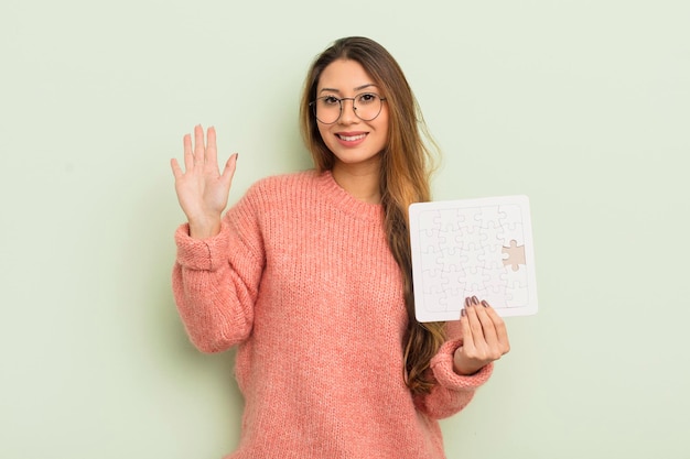 Mujer bonita asiática sonriendo felizmente agitando la mano dándole la bienvenida y saludando el concepto de rompecabezas
