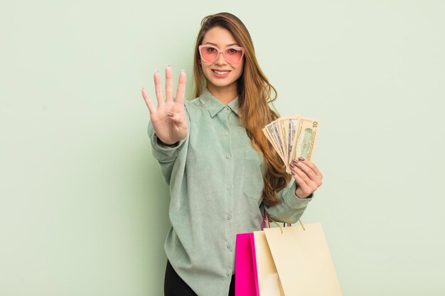 Mujer bonita asiática sonriendo y luciendo amigable mostrando el concepto de bolsas de compras número cuatro