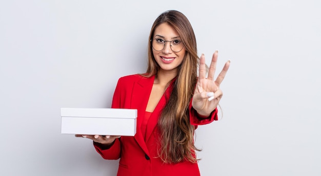 Mujer bonita asiática sonriendo y mirando amigable, mostrando el número tres. concepto de caja en blanco