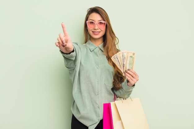 Mujer bonita asiática sonriendo con orgullo y confianza haciendo el concepto de bolsas de compras número uno