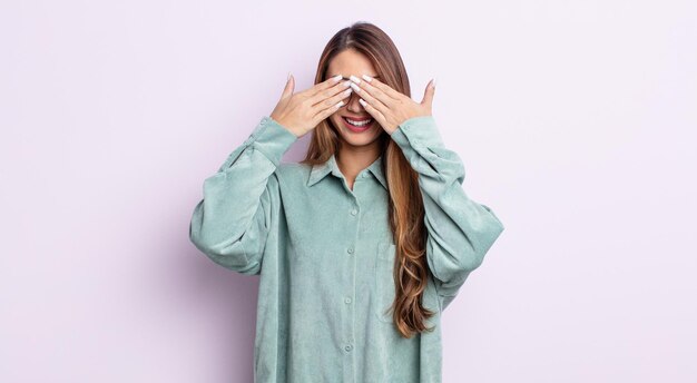 Mujer bonita asiática sonriendo y sintiéndose feliz, cubriendo los ojos con ambas manos y esperando una sorpresa increíble