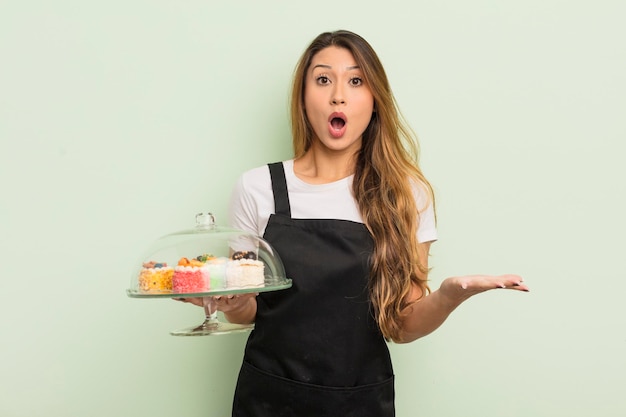 Mujer bonita asiática sorprendida sorprendida y asombrada con un increíble concepto sorpresa de pasteles caseros