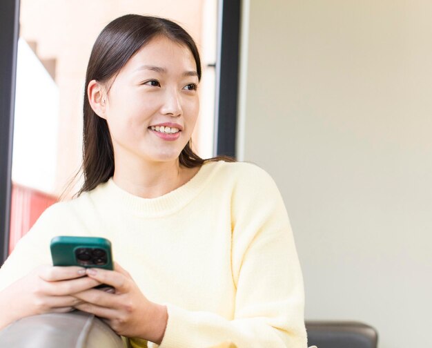 Mujer bonita asiática usando un teléfono inteligente y comprando en casa