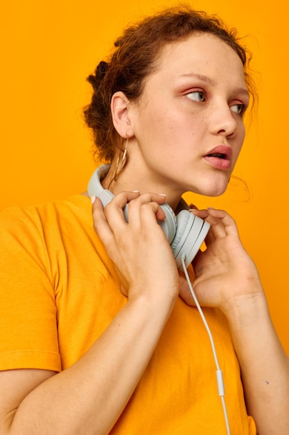 Mujer bonita con auriculares pantalones cortos de mezclilla primer plano emociones fondo amarillo inalterado