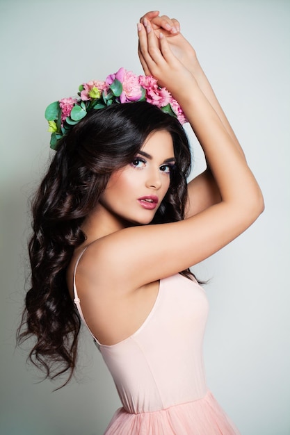 Mujer bonita bailando. modelo de moda con maquillaje, cabello ondulado y flores