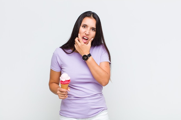 Mujer bonita con la boca y los ojos bien abiertos y la mano en la barbilla