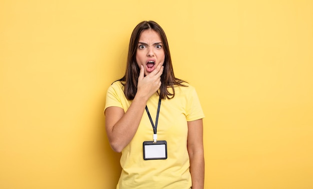 Mujer bonita con la boca y los ojos bien abiertos y con la mano en el mentón concepto de tarjeta de acreditación