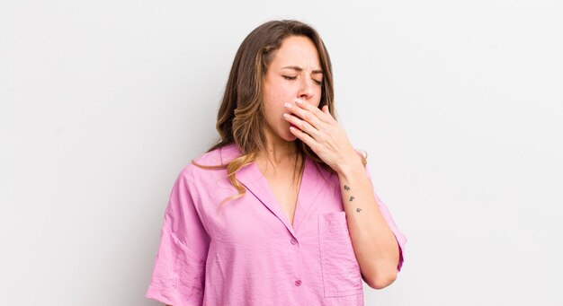 Mujer bonita bostezando perezosamente temprano en la mañana despertándose y luciendo soñolienta, cansada y aburrida