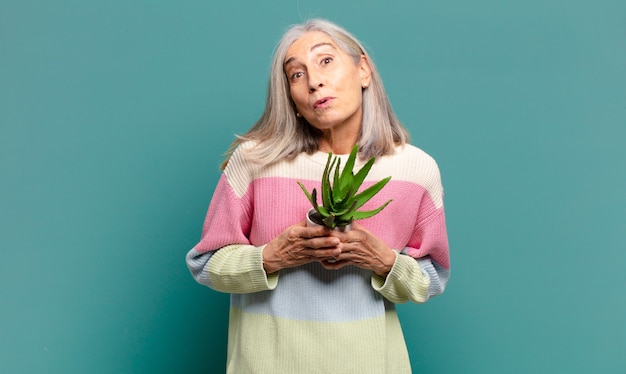 Mujer bonita de cabello gris con un cactus