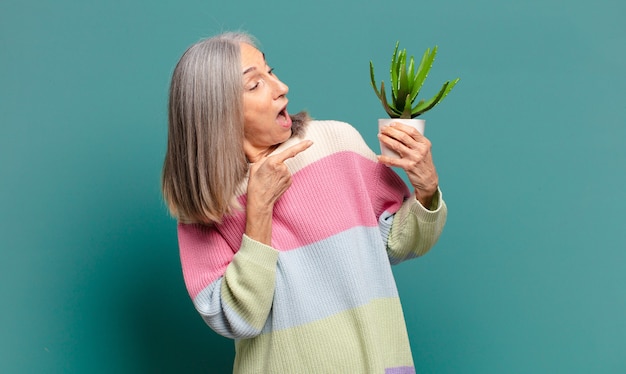 Mujer bonita de cabello gris con un cactus