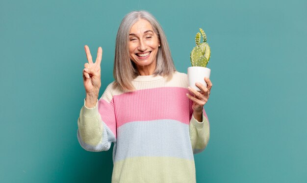 Mujer bonita de cabello gris con un cactus