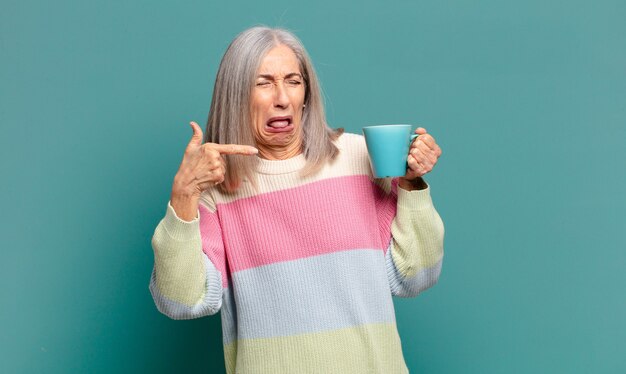 Mujer bonita de cabello gris con un café o un té