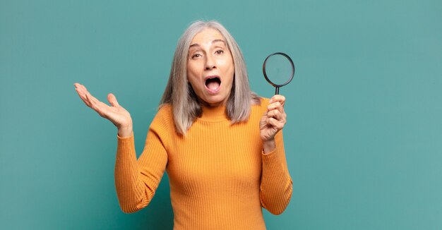 Mujer bonita de cabello gris con una lupa