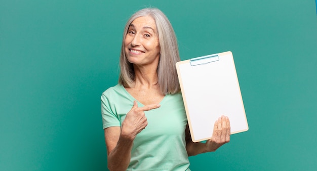Mujer bonita de cabello gris mostrando un trozo de papel vacío