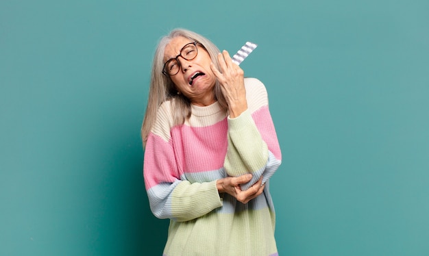 Mujer bonita de cabello gris con pastillas para la enfermedad