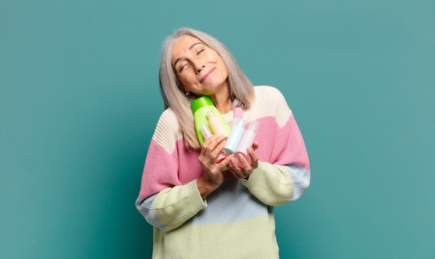 Mujer bonita de cabello gris con productos para el cuidado de la piel