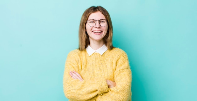 Mujer bonita de cabeza roja que parece una feliz triunfadora orgullosa y satisfecha sonriendo con los brazos cruzados