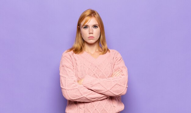 Mujer bonita cabeza roja que se siente disgustada y decepcionada, con aspecto serio, molesto y enojado con los brazos cruzados