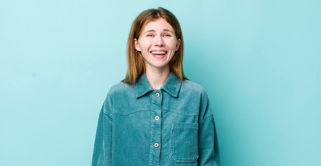 Mujer bonita de cabeza roja que se ve feliz y gratamente sorprendida emocionada con una expresión fascinada y conmocionada