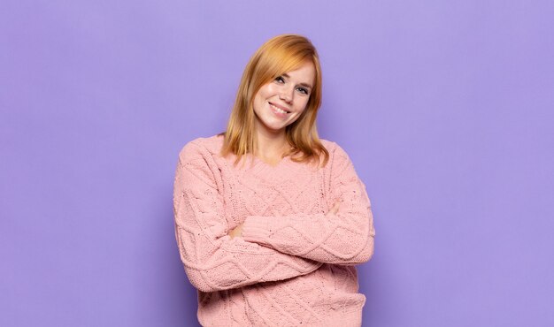 Mujer bonita cabeza roja riendo felizmente con los brazos cruzados, con una pose relajada, positiva y satisfecha