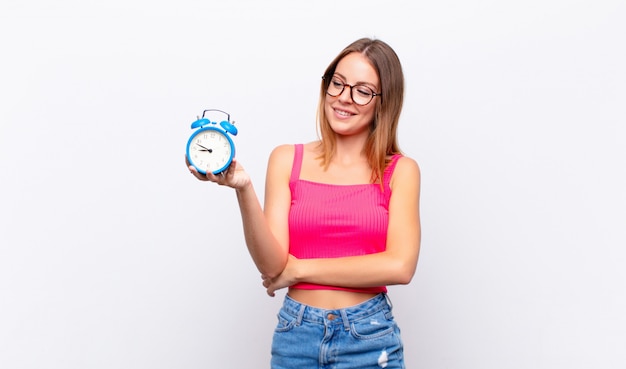 Foto mujer bonita cabeza roja sosteniendo un reloj despertador y expresando un concepto