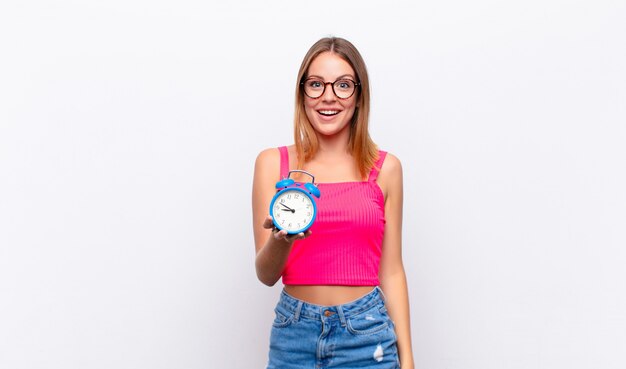 Mujer bonita cabeza roja sosteniendo un reloj despertador y expresando un concepto