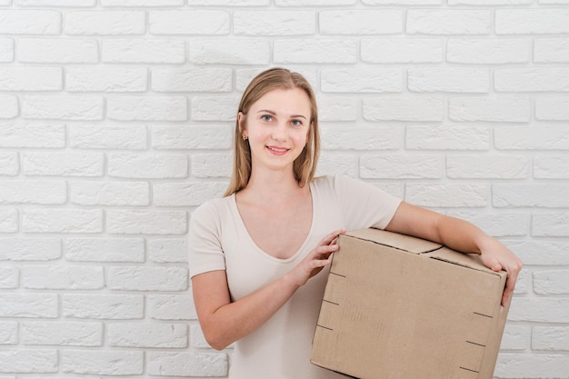 Mujer bonita con una caja de cartón entregando un paquete