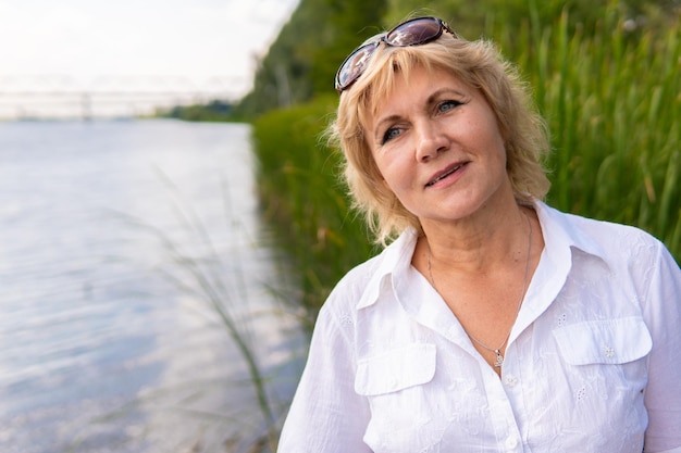 Una mujer bonita camina por el parque en la naturaleza. Se encuentra junto al lago.