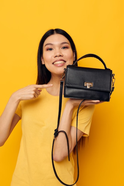 Mujer bonita en camiseta amarilla bolso negro posando moda