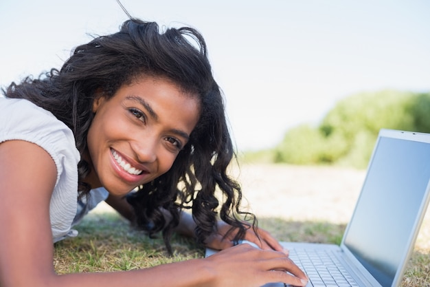 Mujer bonita casual tirado en el pasto con su computadora portátil
