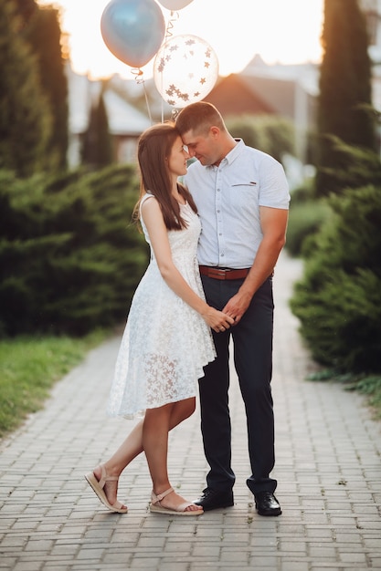 Mujer bonita caucásica con cabello largo ondulado oscuro en vestido blanco abraza con hombre hermoso