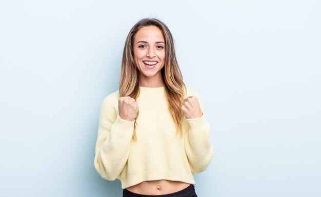 Mujer bonita caucásica gritando triunfalmente, riendo y sintiéndose feliz y emocionada mientras celebra el éxito