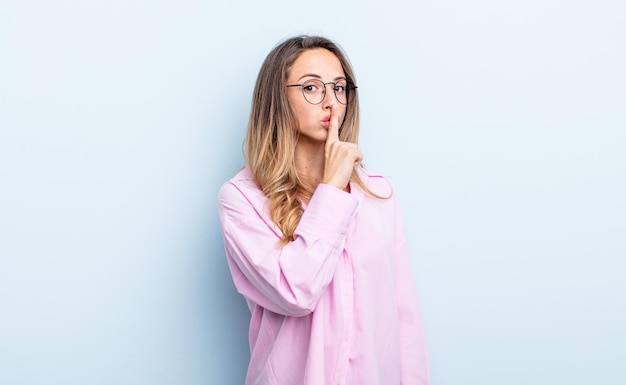 Mujer bonita caucásica pidiendo silencio y silencio, gesticulando con el dedo delante de la boca, diciendo shh o guardando un secreto