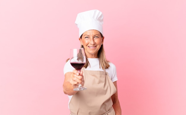 Mujer bonita chef de mediana edad con una copa de vino