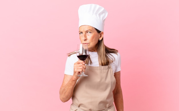 Mujer bonita chef de mediana edad con una copa de vino