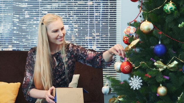 Mujer bonita colgando bolas en el árbol de Navidad