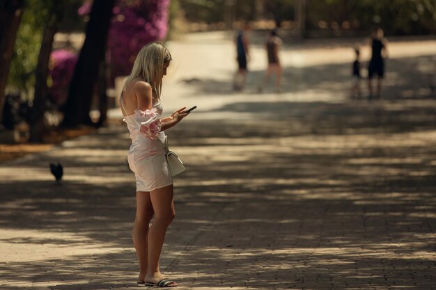 Una mujer bonita se comunica en un parque de la ciudad en un teléfono inteligente