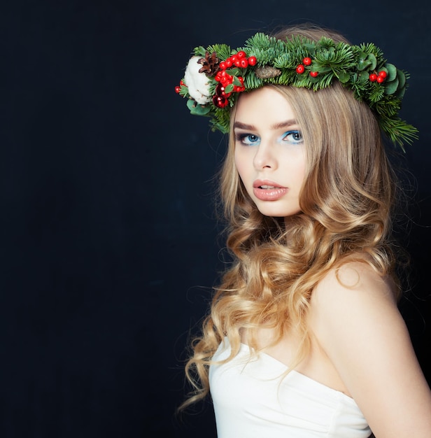 Mujer bonita con corona de Navidad en fondo negro