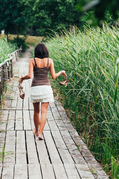 Mujer bonita delgada se aleja, tacones altos en las manos