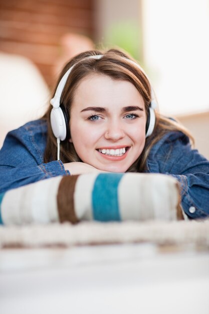 Mujer bonita escuchando música tirada en el suelo