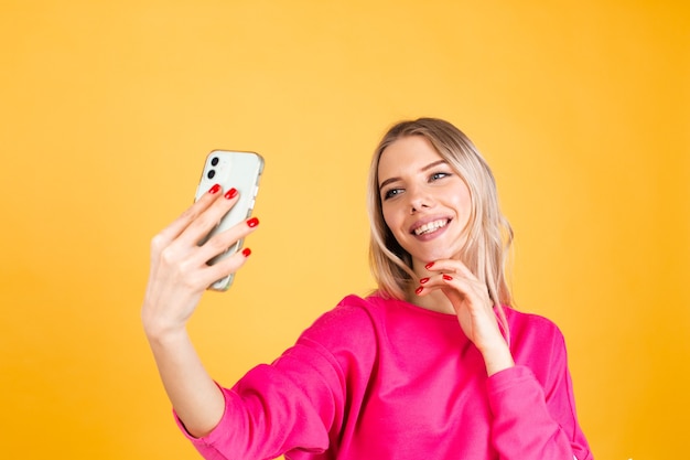 Mujer bonita europea en blusa rosa sobre pared amarilla