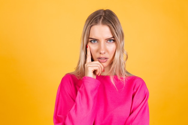 Mujer bonita europea en blusa rosa sobre pared amarilla