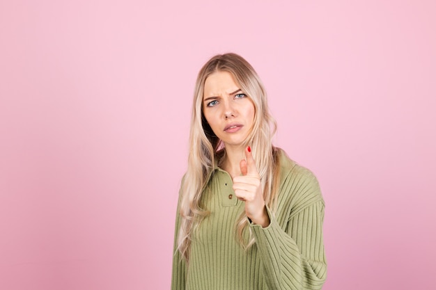 Mujer bonita europea en suéter casual en pared rosa