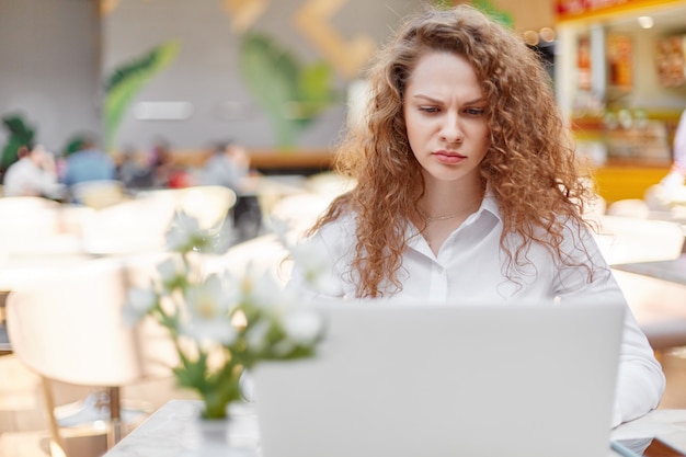 Mujer bonita con expresión insatisfecha trabaja en la computadora portátil